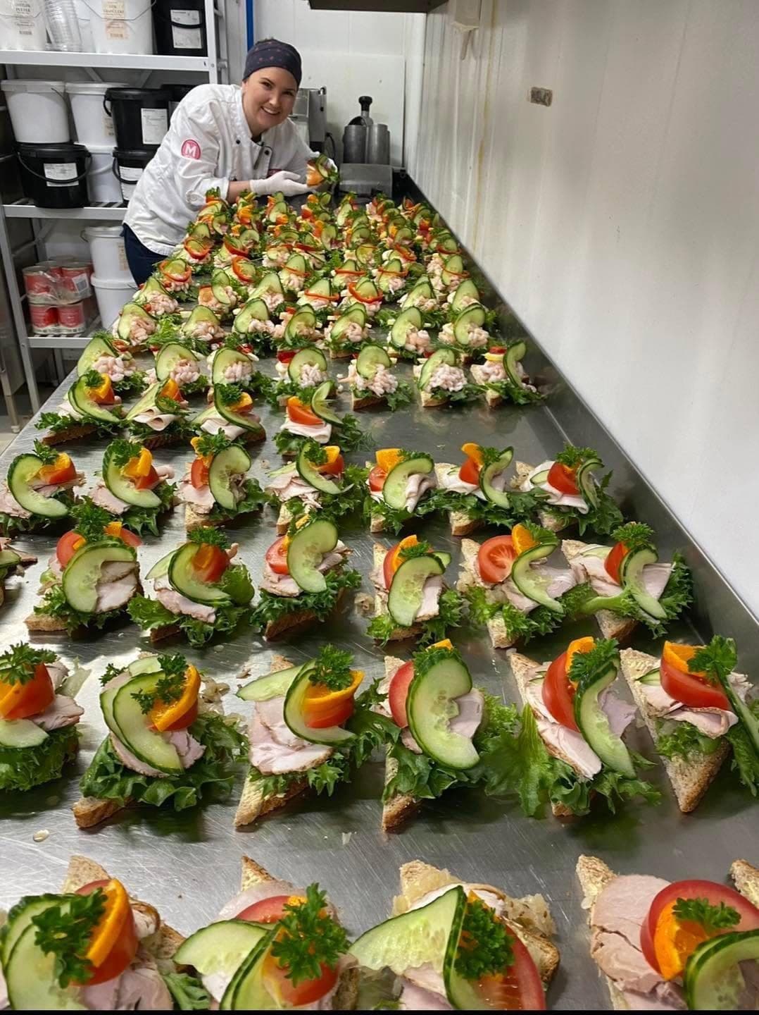 Kokk i MENY Blinken pynter lange rader med snitter på kjøkkenbenken.