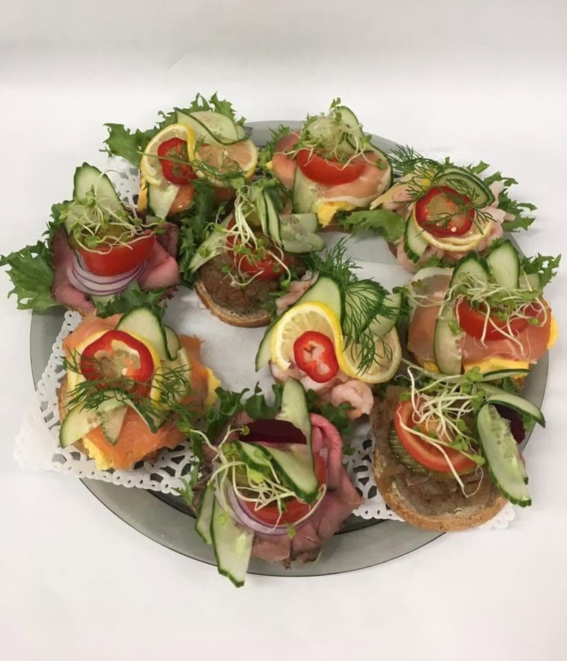 Rundt fat med snitter på spiralloff: roastbiff, røkelaks, reker og skinke, pyntet med agurk, sitron og dill.